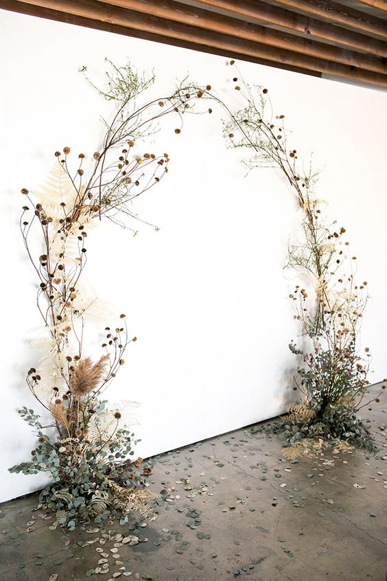 a beautiful wedding arch covered with dried blooms and leaves and greenery is a stylish and trendy idea for a wedding