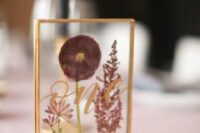 31 a lovely pressed flower wedding table number with a gold frame and gold calligraphy is a very pretty idea