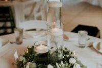 37 a minimalist winter wedding tablescape with a greenery and white flower wreath, candles, floating and usual ones and white linens