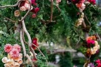 39 a secret garden wedding arch decorated with greenery and evergreens, bold blooms in hot pink, purple, burgundy, blush blooms and branches weaving the arch