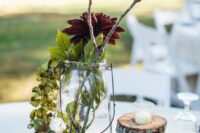 42 a fall wedding centerpiece with a wood slice, pinecones, greenery, branches and burgundy blooms looks very cozy and rustic