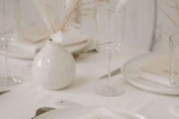 43 a neutral winter wedding table with white porcelain, dried grasses in vases, cutlery with black handles and neutral menus
