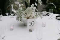 45 a sophisticated minimalist wedding tablescape with a crispy white tablecloth, black plates and grey napkins, neutral blooms and candles