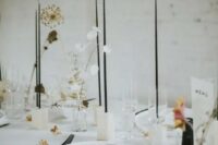 46 a stylish minimalist wedding tablescape with white plates and linens, white candleholders, tall and thin black candles and dried and fresh blooms