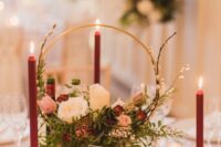 a refined Christmas hoop wedding centerpiece with white, pink and burgundy blooms, red blooms around and small candleholders