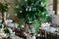 52 a woodland wedding centerpiece of a tree stump, white blooms, greenery and candle holders hanging on branches