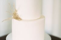 55 a pure white wedding cake with dried grasses is a stylish idea for a minimalist fall or winter wedding