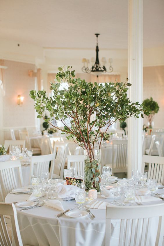 a stylish wedding centerpiece of greenery branches and with foliage inside the vase is a very pretty and natural idea