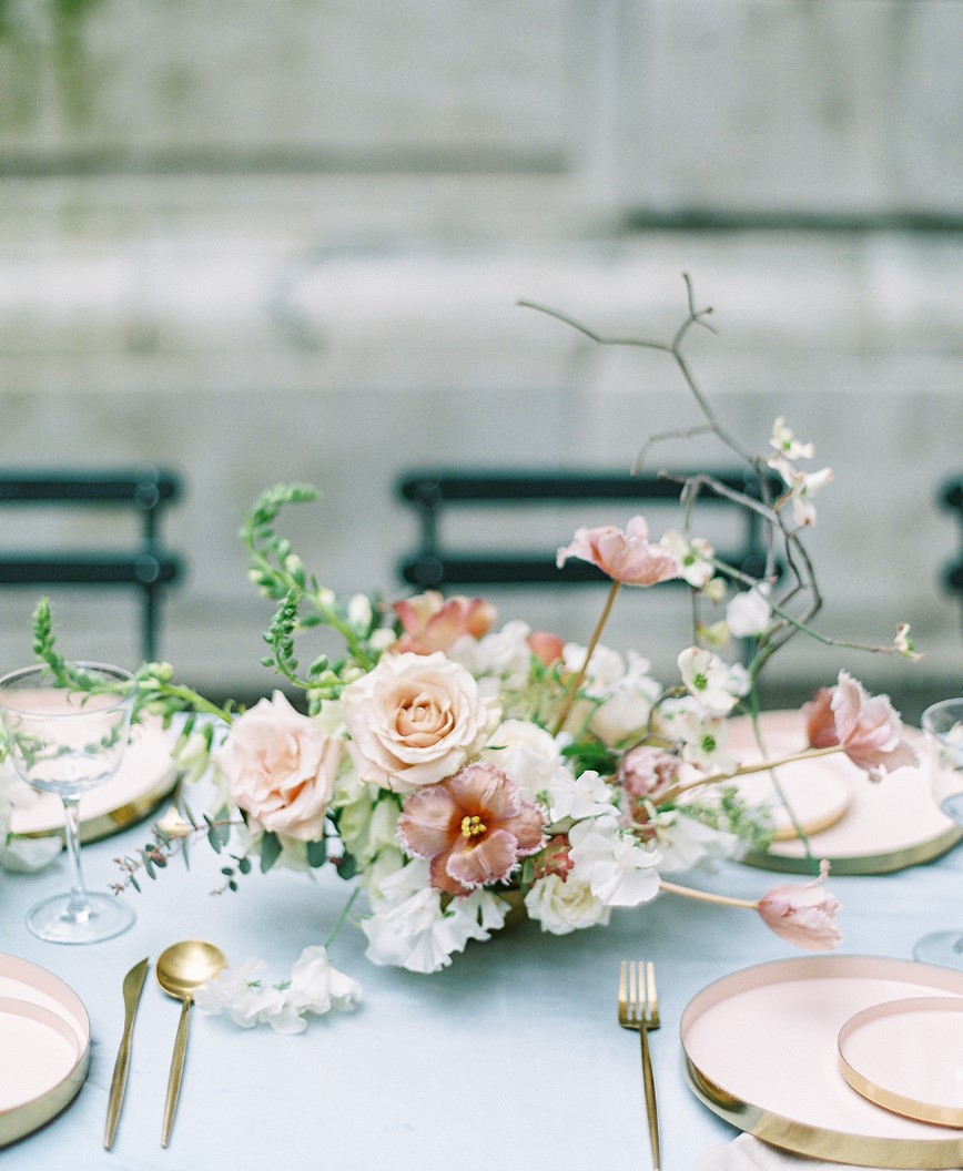 a sophisticated wedding centerpiece cohesively incorporates twigs into a lush, bloom focused arrangement for a unique look