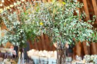 59 tall wedding centerpieces of greenery branches and some additional greenery on the table for a botanical feel