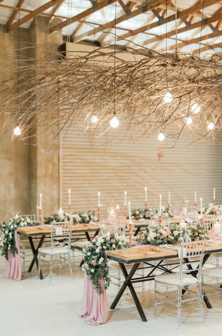such overhead installations of branches and twigs will add interest to the space and will contrast the romantic floral centerpieces on the tables