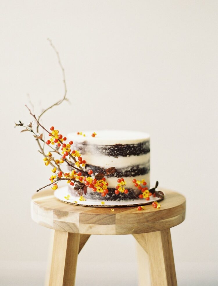 a naked one-tier wedding cake with an over-the-top presence thanks to twig and berry accents