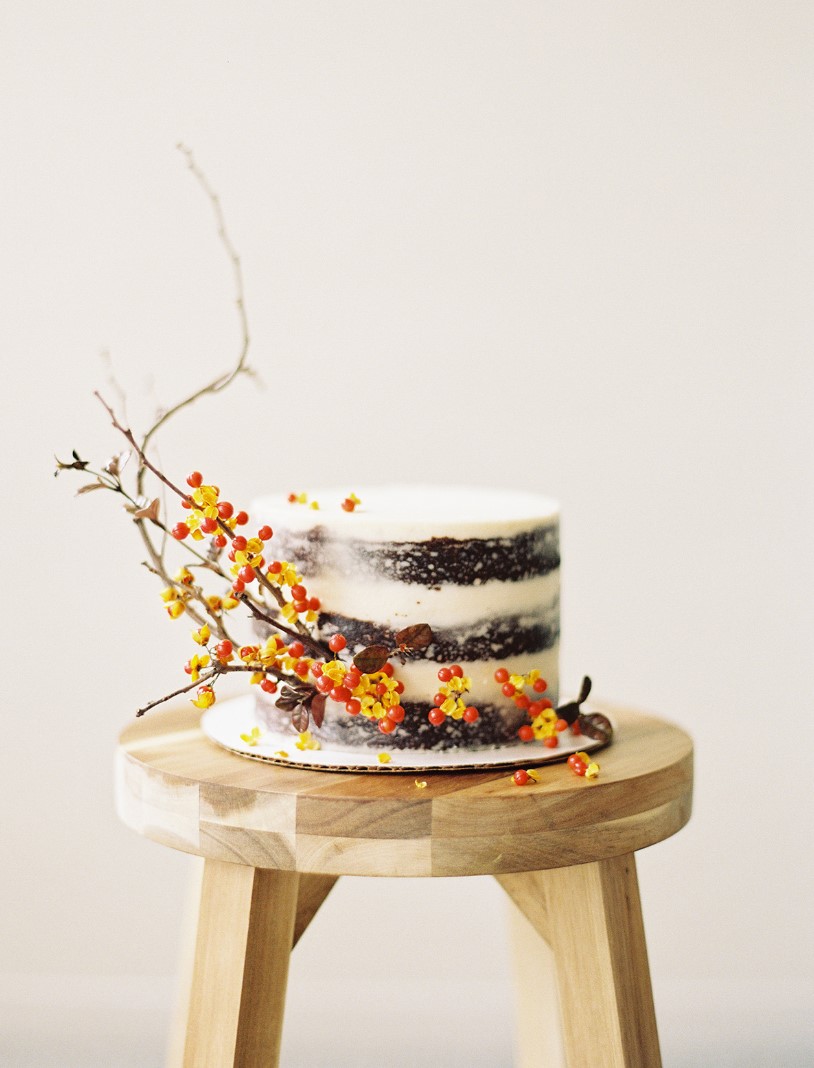 a naked one tier wedding cake with an over the top presence thanks to twig and berry accents