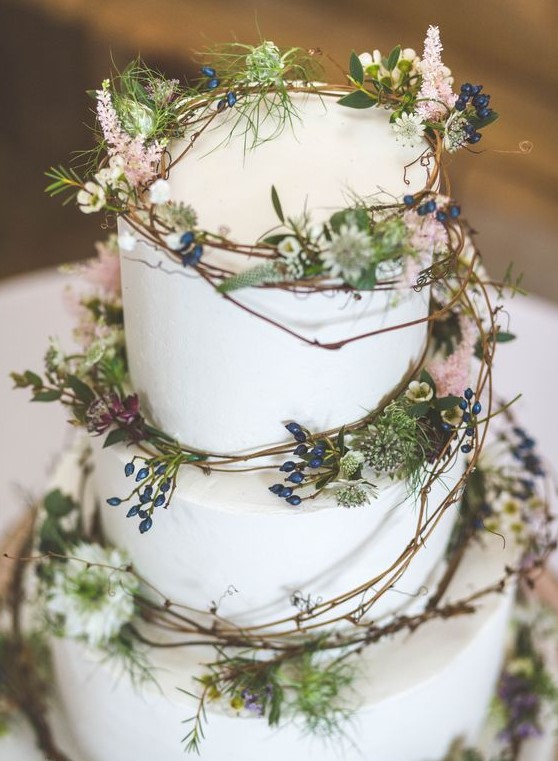 a plain white wedding cake decorated with vine, greenery, berries and pink blooms is ideal for a woodland wedding