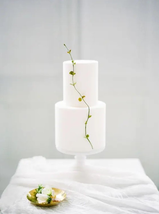 a pure white minimalist wedding cake decorated with a single fresh twig is amazing for a spring wedding