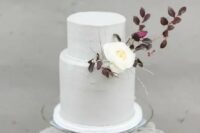 69 a purely white wedding cake decorated with dark foliage and a single white blooms for an early fall wedding with a Nordic twist