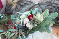a Christmas wedding bouquet of evergreens, blush and burgundy roses, greenery and dark foliage is chic