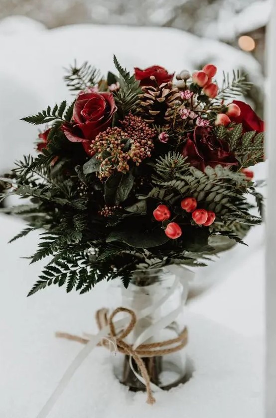a beautiful Christmas wedding bouquet of greenery, red roses, berries and pinecones is a very cool option