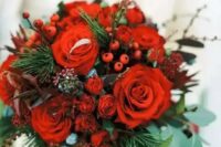 a bold Christmas wedding bouquet of red blooms, berries, greenery and fir branches is bright