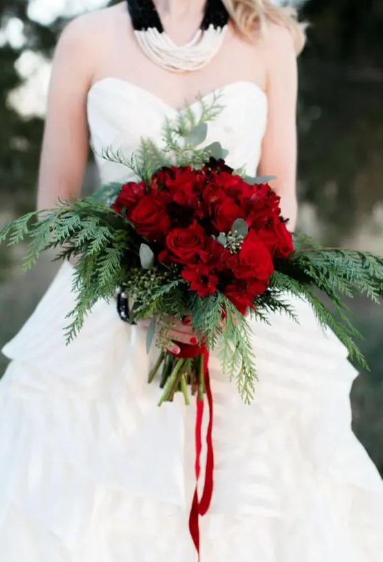 a bright and chic Christmas wedding bouquet of red roses and ferns plus red ribbons is gorgeous