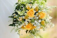 a bright and chic wedding bouquet that includes yellow roses, billy balls, daisies, ferns and greenery for a summer wedding