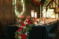 a cascading holiday-inspired table runner with magnolia leaves, evergreens, red roses and pinecones for a festive wedding