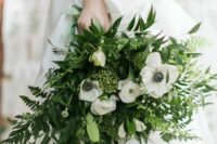a catchy wedding bouquet of fern, leaves, white anemones and other greenery is a stylish idea for any bride
