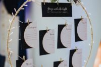 a celestial wedding seating chart with phases of the moon, lights and greenery on top is a lovely idea for such a wedding