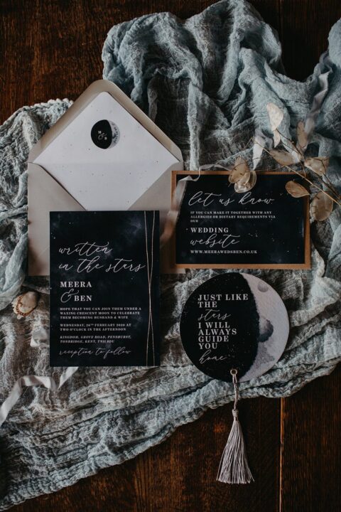 a chic celestial wedding invitation suite in black, grey and white, with half moons, a tassel and some lunaria
