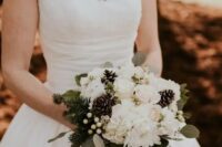 a chic winter wedding bouquet of white blooms, greenery, evergreens, berries and pinecones is a traditional idea for an elegant winter wedding
