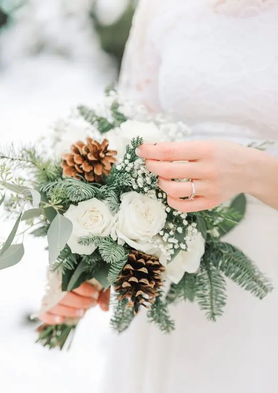 a delicately and lovely winter wedding bouquet of white roses, baby's breath, evergreens and eucalyptus is an amazing winter idea