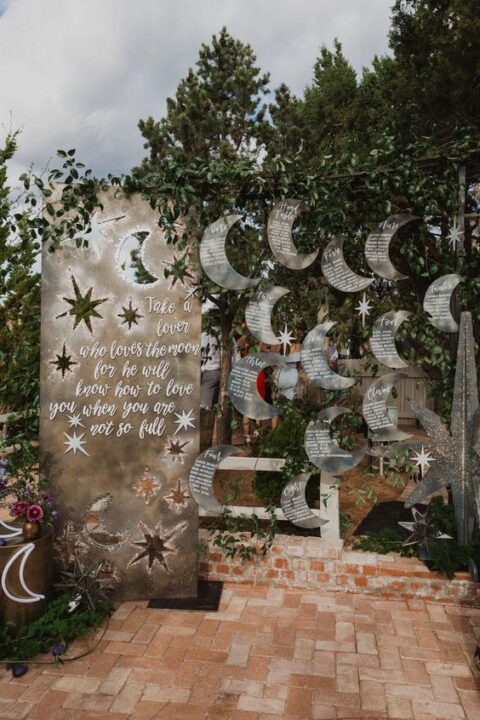 a fab celestial wedding seating chart with a large sign, greenery and grey half moon hangings is amazing for a celestial wedding