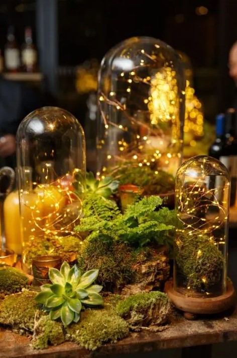 a fairy woodland wedding centerpiece with cloches with lights, moss, greenery and succulents is a gorgeous idea for your enchanted forest celebration