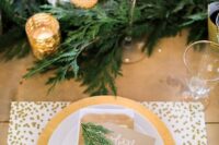 a festive winter wedding tablescape with evergreens, candles, polka dot placemats and gold chargers