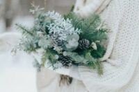 a greenery winter wedding bouquet with evergreens, pinecones and some white blooms is a great idea for a winter bride