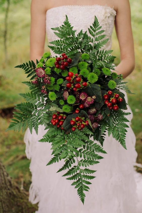 a jaw dropping Christmas wedding bouquet with fern, green and burgundy blooms and berries just wows