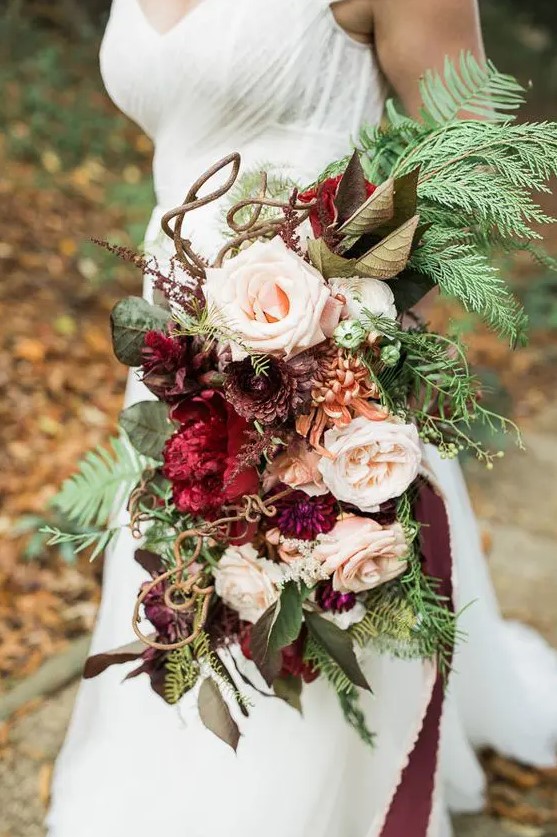 a jaw-dropping woodland wedding bouquet with blush and purple blooms, with foliage, fern and twigs is all cool