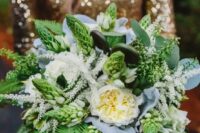 a lovely and dimensional wedding bouquet of various types of greenery and white blooms and pale leaves for a woodland wedding