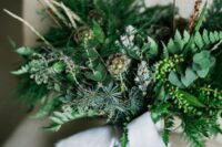 a lovely and textural wedding bouquet of greenery and evergreens, twigs and berries, seed pods and grey ribbon