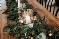 a lovely evergreen table runner with berries and greenery plus various candles – both pillar and tall and thin ones