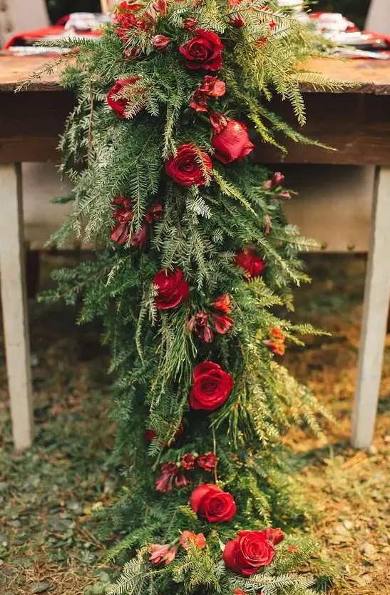 a lush evergreen table runner with red roses looks stunning on any table and adds rustic chic