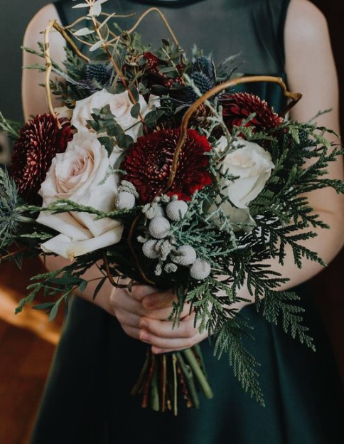 a lush winter wedding bouquet with red and blush blooms, thistles, vine, ferns and berries