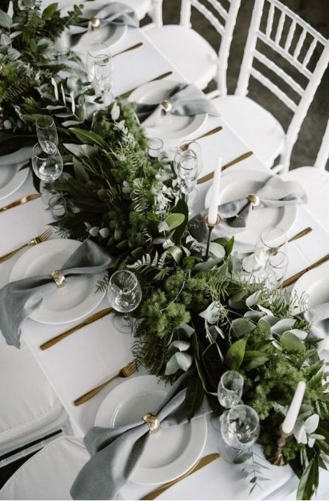 a lush woodland inspired greenery table garland with various kinds of eucalyptus, moss and ferns