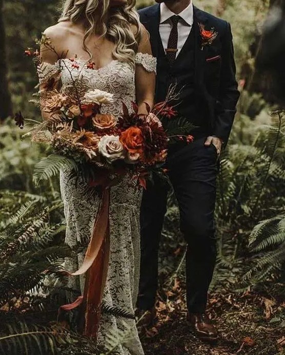 a luxurious moody woodland wedding bouquet of orange, burgundy, creamy and coffee blooms, branches with berries and long ribbons