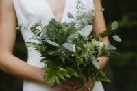 a minimalist white wedding dress with a deep neckline and a stylish fern and seeded eucalyptus wedding bouquet for a modern wedding