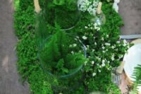 a moss and fern table runner with tiny white blooms and candles is a perfect fit for a woodland wedding
