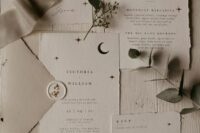 a neutral celestial wedding invitation suite with black stars and half moons and delicate lettering is a stylish and soft idea to try