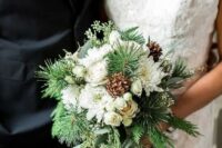 a pretty and chic winter wedding bouquet of white blooms, evergreens and pinecones is a simple and lovely idea for an elegant celebration