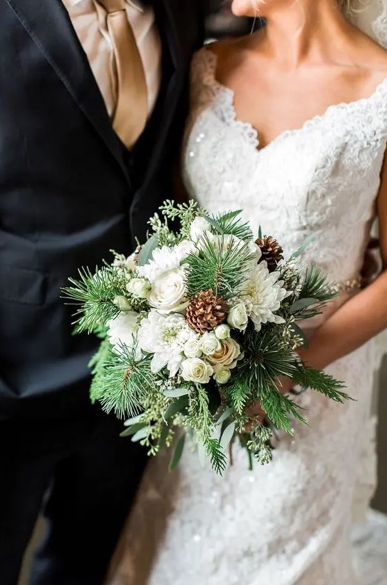 a pretty and chic winter wedding bouquet of white blooms, evergreens and pinecones is a simple and lovely idea for an elegant celebration