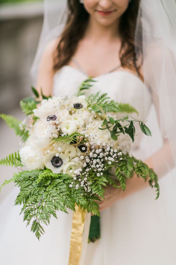 a pretty wedding bouquet of fern, white anemones, ranunculus and baby's breath plus yellow silk ribbons